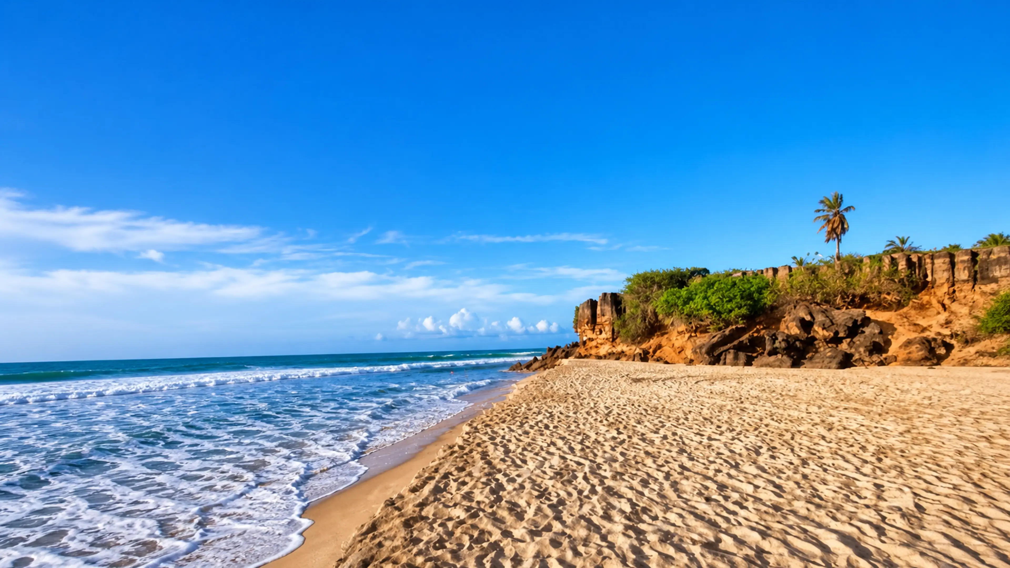 Praia de Tourinhos com faixa de areia, mar e falésias